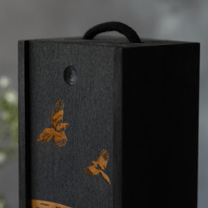 Detail of decorative wine box with laser-engraved magpies on a grey background.