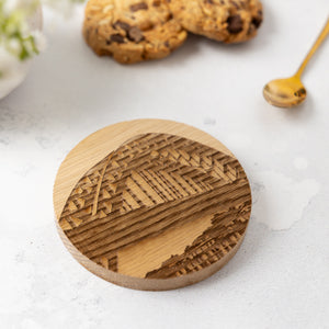 Wooden coaster with laser-engraved Tyne Bridge artwork on a light surface with cookies and a spoon in the background