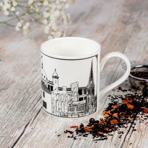 Fine china mug featuring landmarks from Tynemouth, Cullercoats, Whitley Bay and North Shields. With a silver tea strainer and scattered tea leaves.