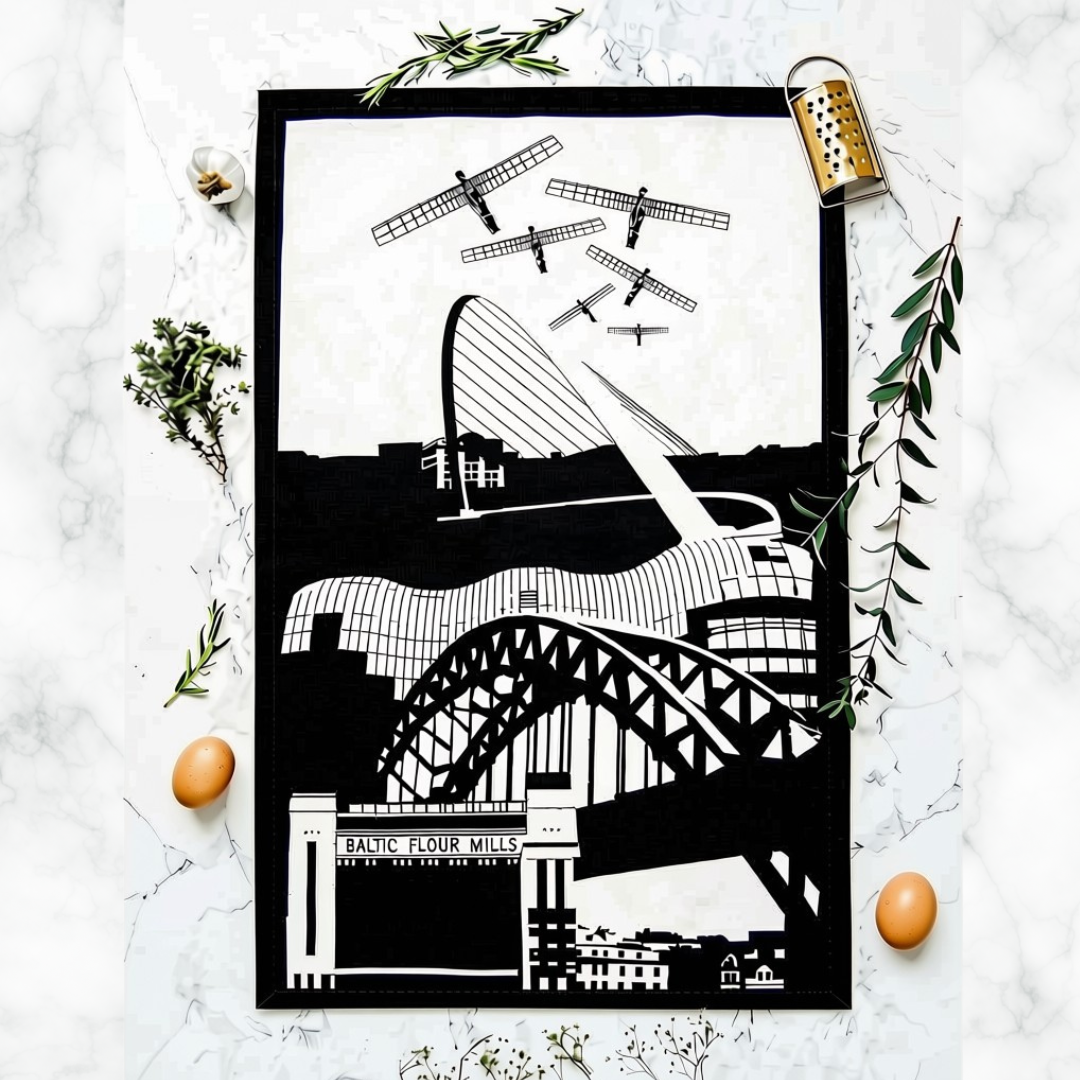 A black and white art print featuring iconic landmarks of Newcastle, including the Angel of the North, Millennium Bridge, Tyne Bridge, the Glasshouse and Baltic Flour Mill, styled in a flat-lay on a white marble background with green fresh herbs and eggs.