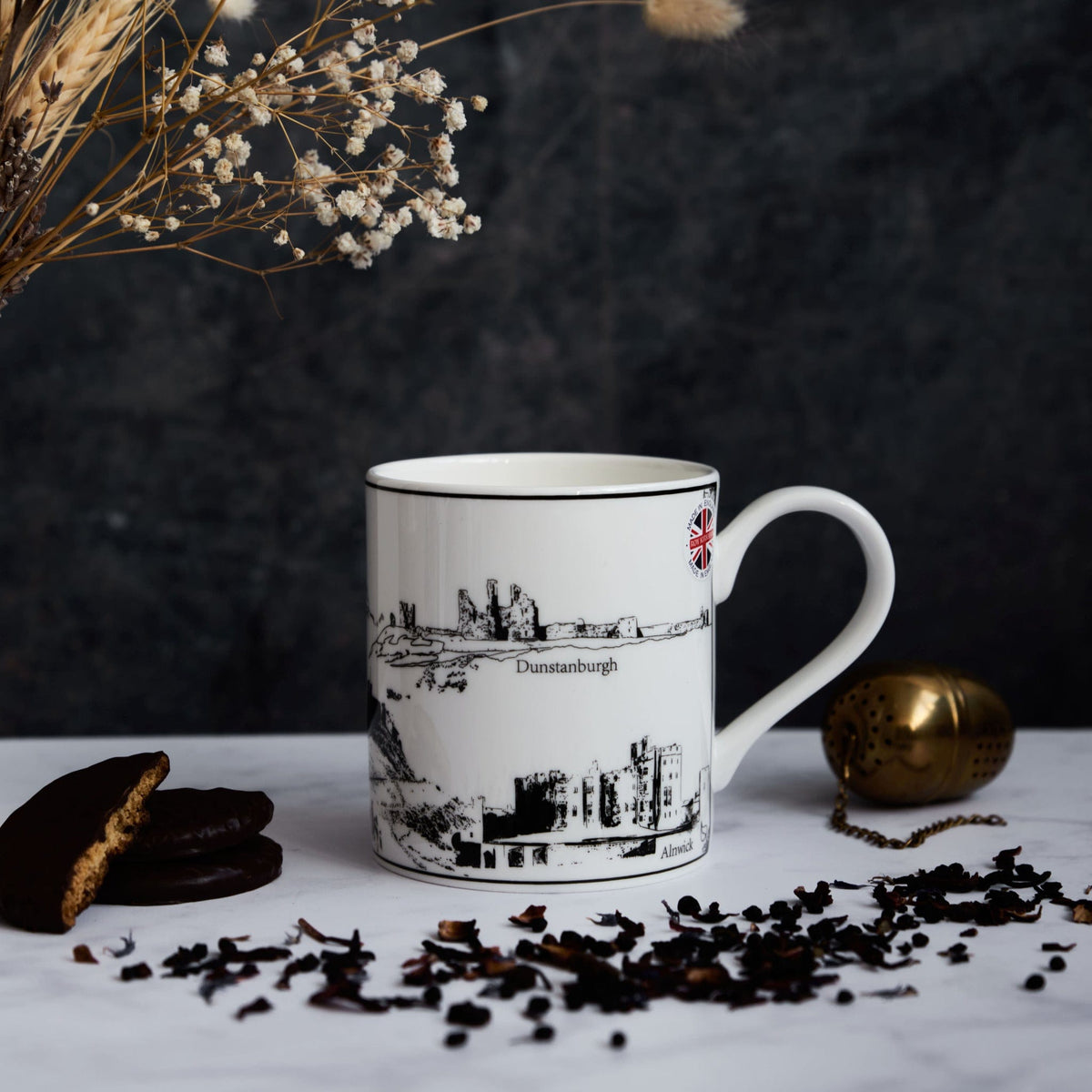 white ceramic mug with black and white illustration of dunstanburg castle by powder butterfly