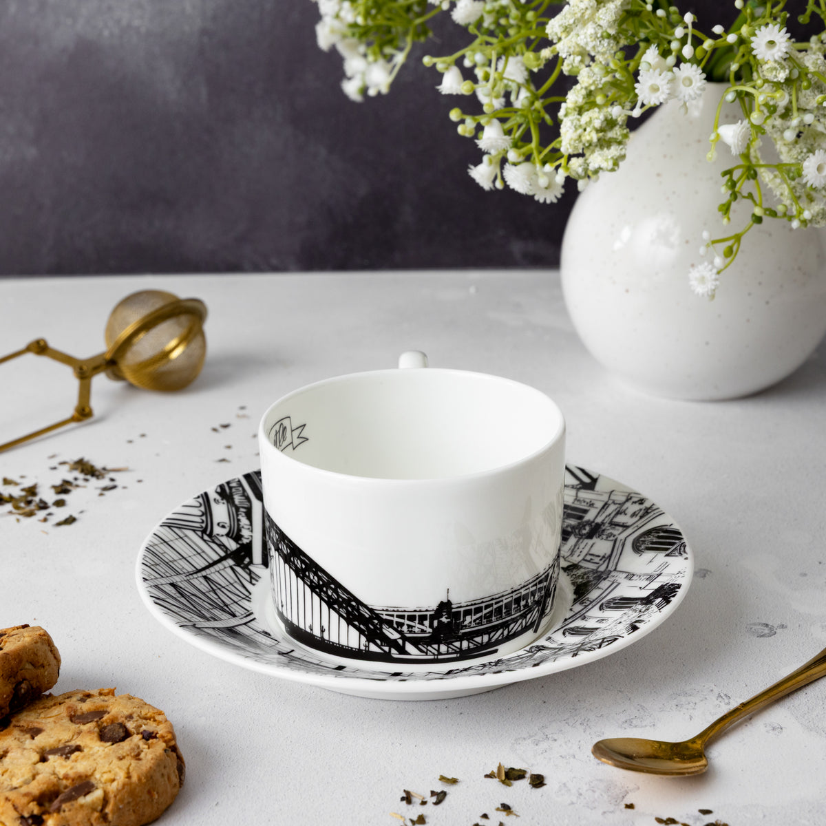 Side image of the Newcastle tea cup and saucer set by powder Butterfly featuring a black and white print of Newcastle landmarks.