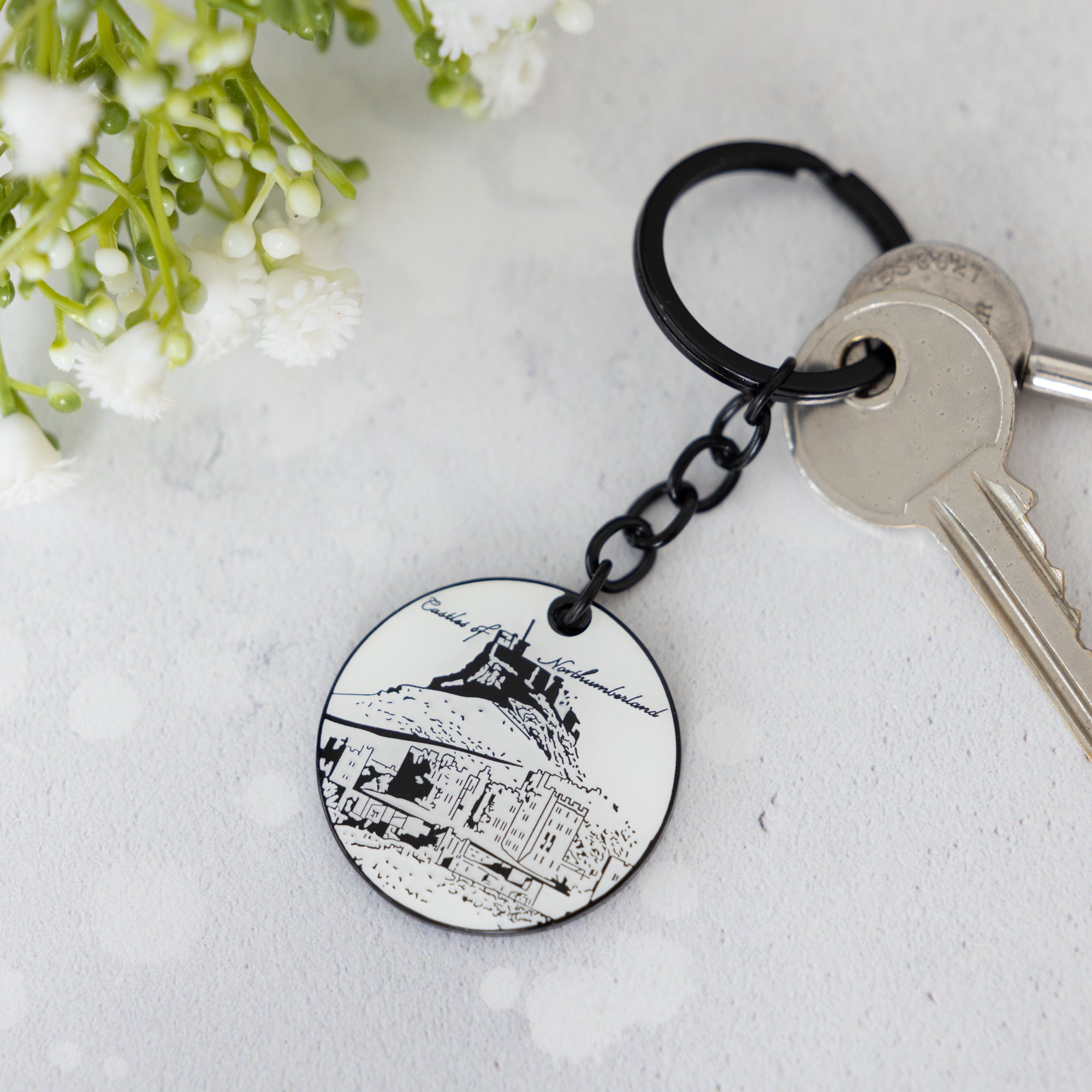 Powder Butterflys enamel keyring illustrated with northumberland castles in black and white