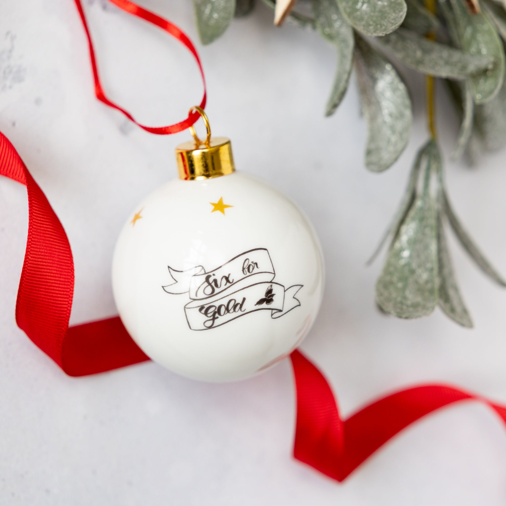 Black and white enamel bauble illustrated with a magpie in black and white and gold trim