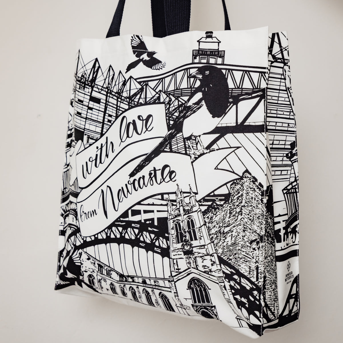 angled view of the newcastle landmarks themed tote bag by powder butterfly illustrated in black and white
