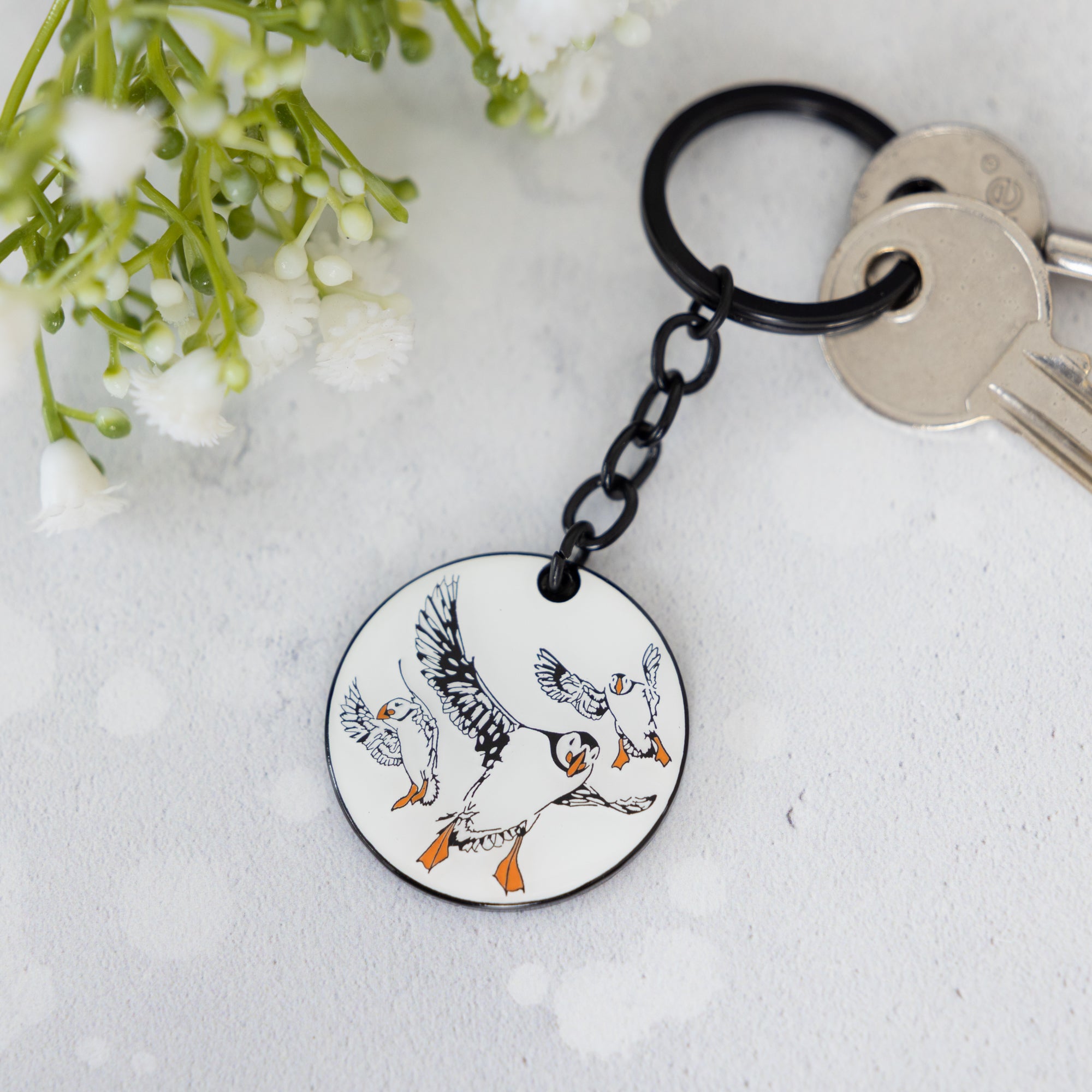 black and white illustrated enamel keyring by powder butterfly featuring the famous puffin