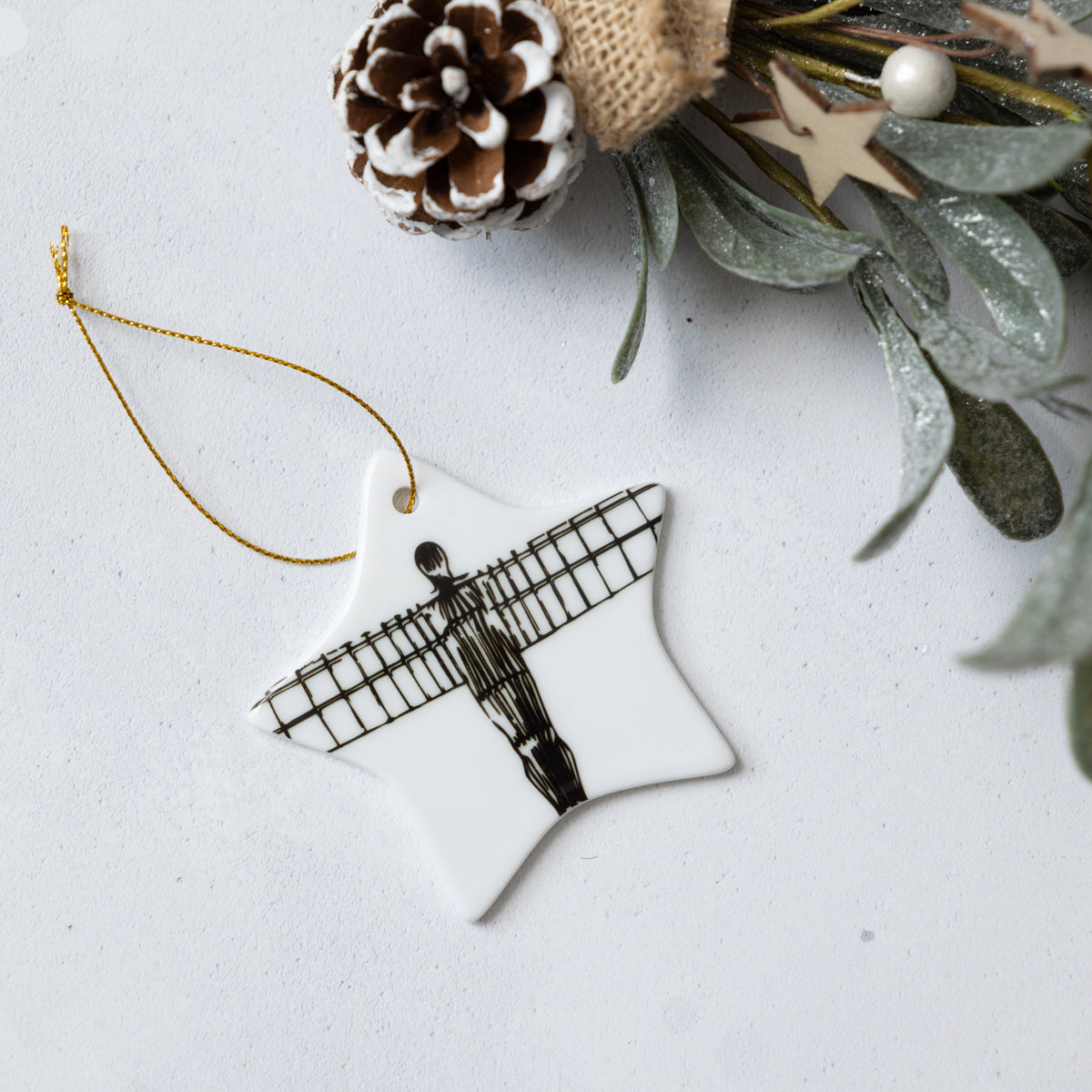 Star-shaped ornament with a black and white Angel of the North design on a light gray background with decorative elements.