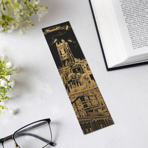 Decorative bookmark with Manchester-themed architectural design on a white surface with flowers and glasses.