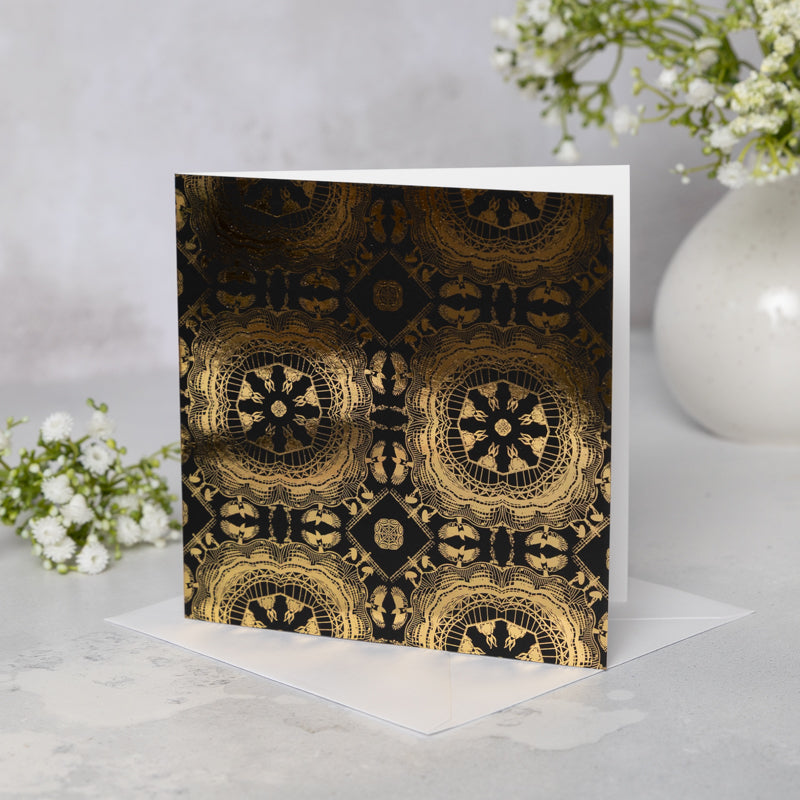 Black soft-touch greeting card with Newcastle landmarks-themed gold mandala patterns on a white background with white flowers in a vase.