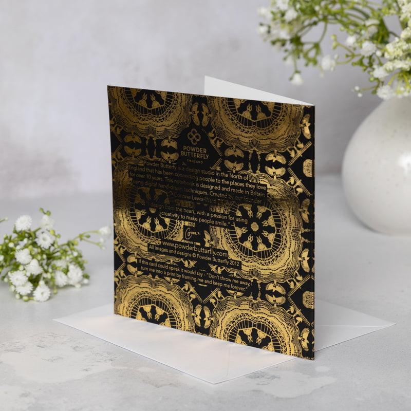 Bacl of the black soft-touch greeting card with Newcastle landmarks-themed gold mandala patterns on a white surface.