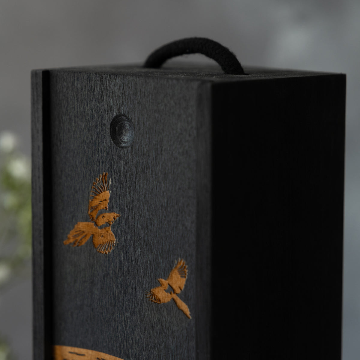 Detail of decorative wine box with laser-engraved magpies on a grey background.