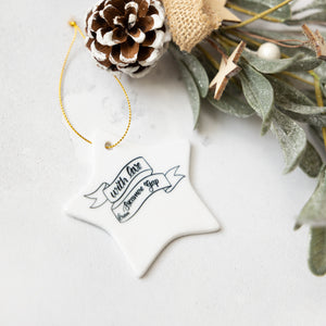 Decorative star ornament with text 'With love from Sycamore Gap', pine cone and greenery on a light background