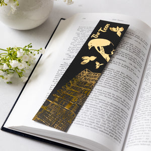 Black and gold bookmark on an open book with decorative elements.