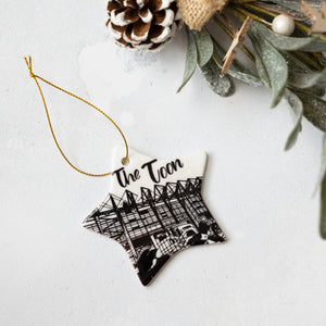 Decorative ornament with 'The Toon' text and St James Park silhouette design with two magpies on a white background.