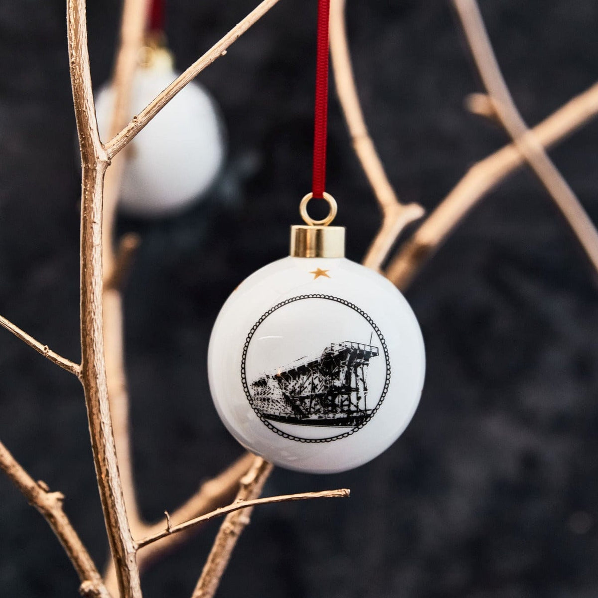 White ceramic holiday ornament by powder butterfly featuring a black and white illustration of Dunston staiths complete with red ribbon and gold trim