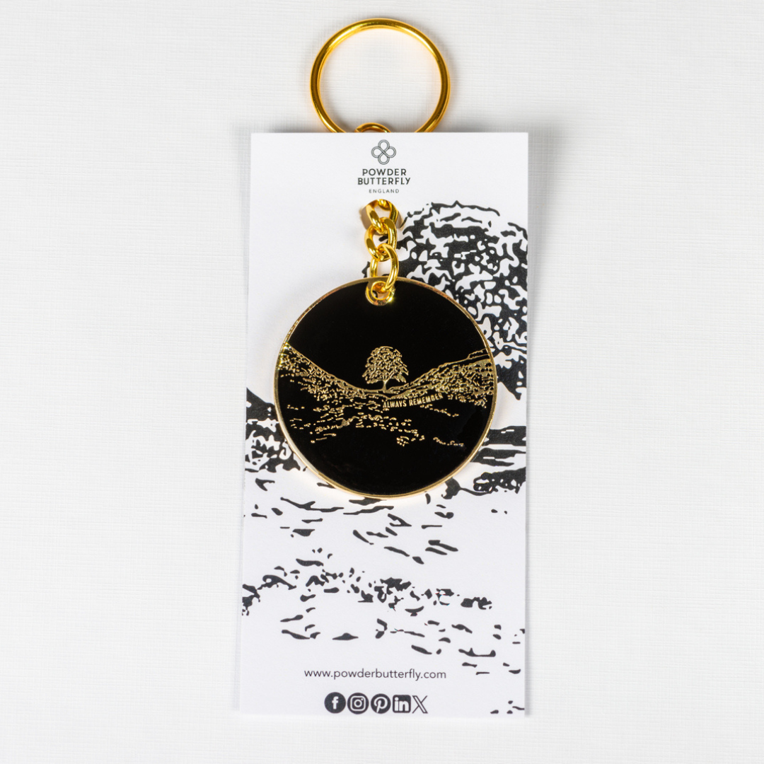 a black keyring with gold trim and illustrations featuring sycamore gap.