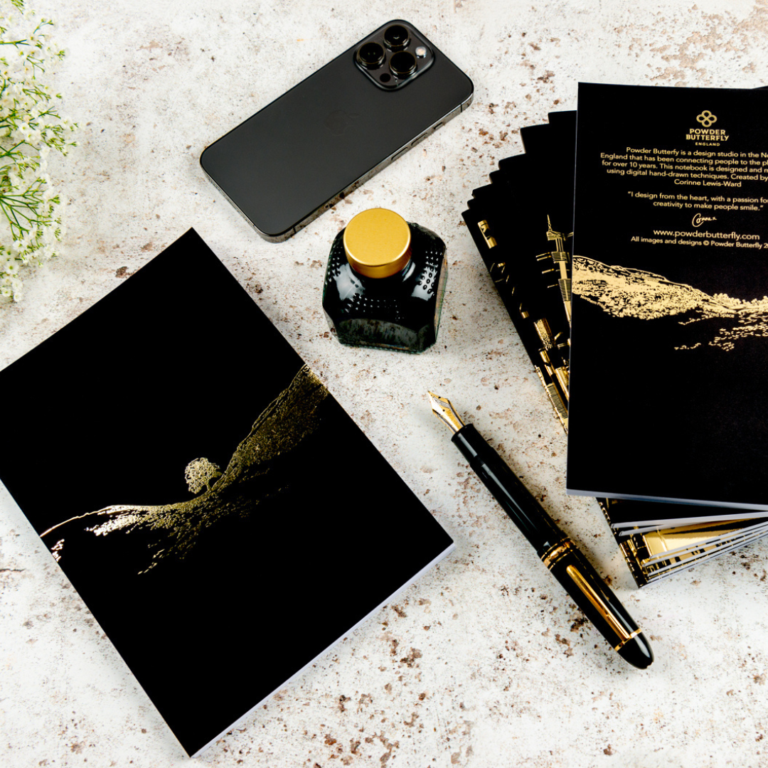 a black notebook featuring gold foil illustrations of sycamore gap before it was felled.