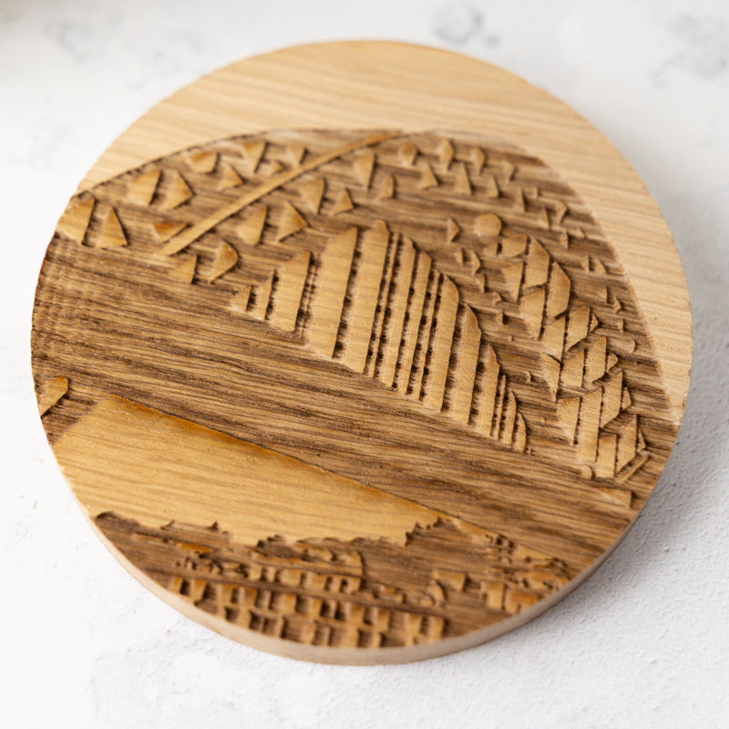 Round wooden coaster with laser-engraved Tyne Bridge artwork design on a light background