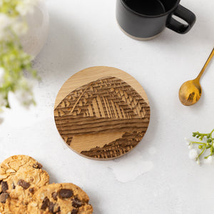 Wooden coaster with Tyne Bridge laser-engraved artwork on a white surface with cookies and a mug.